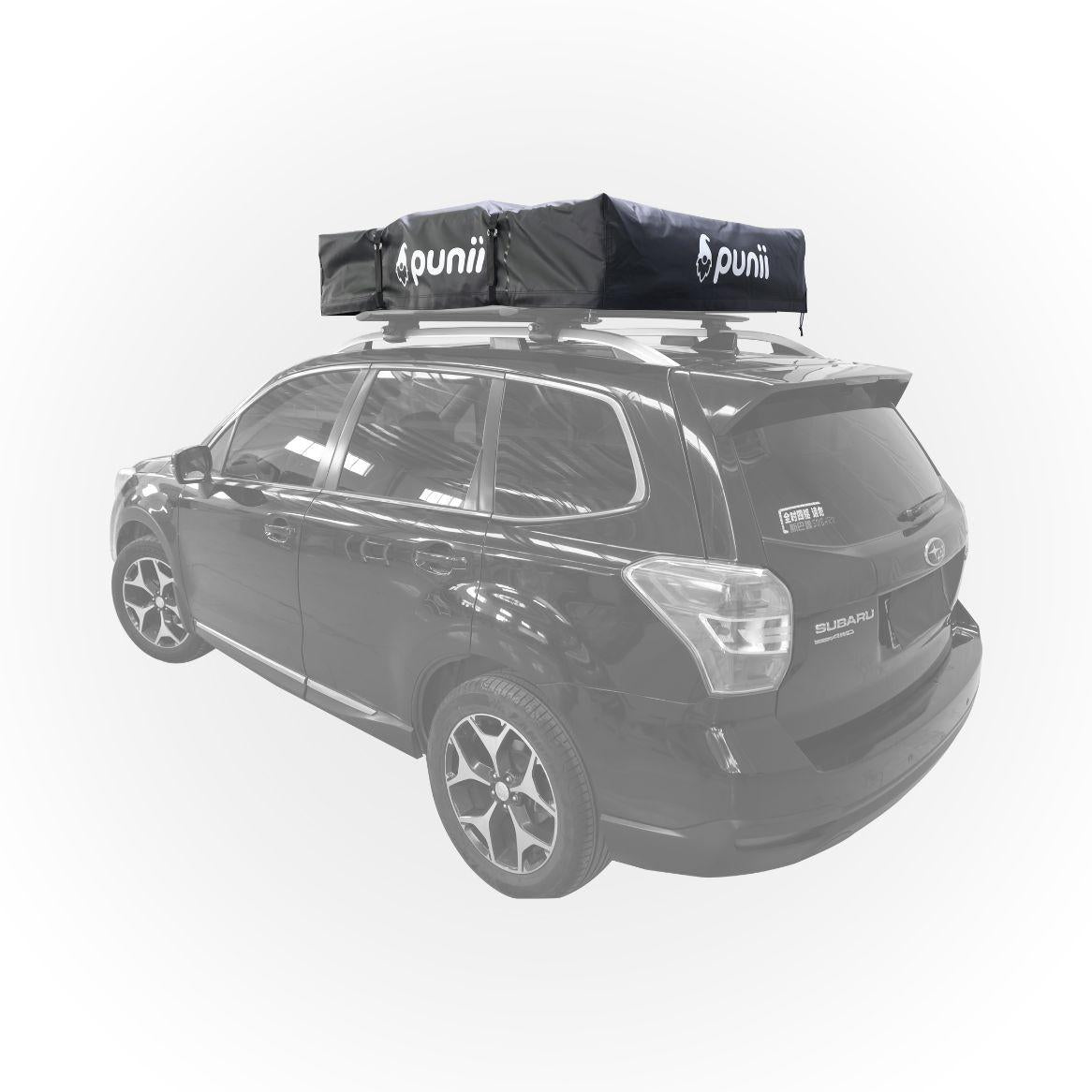 Dachzelt moenga im verpackten Zustand mit einer Leiter auf einem Auto. Das Transportcover mit punii Logo ist verschlossen und die Spanngurte sind verzurrt. Ansicht von seitlich hinten.